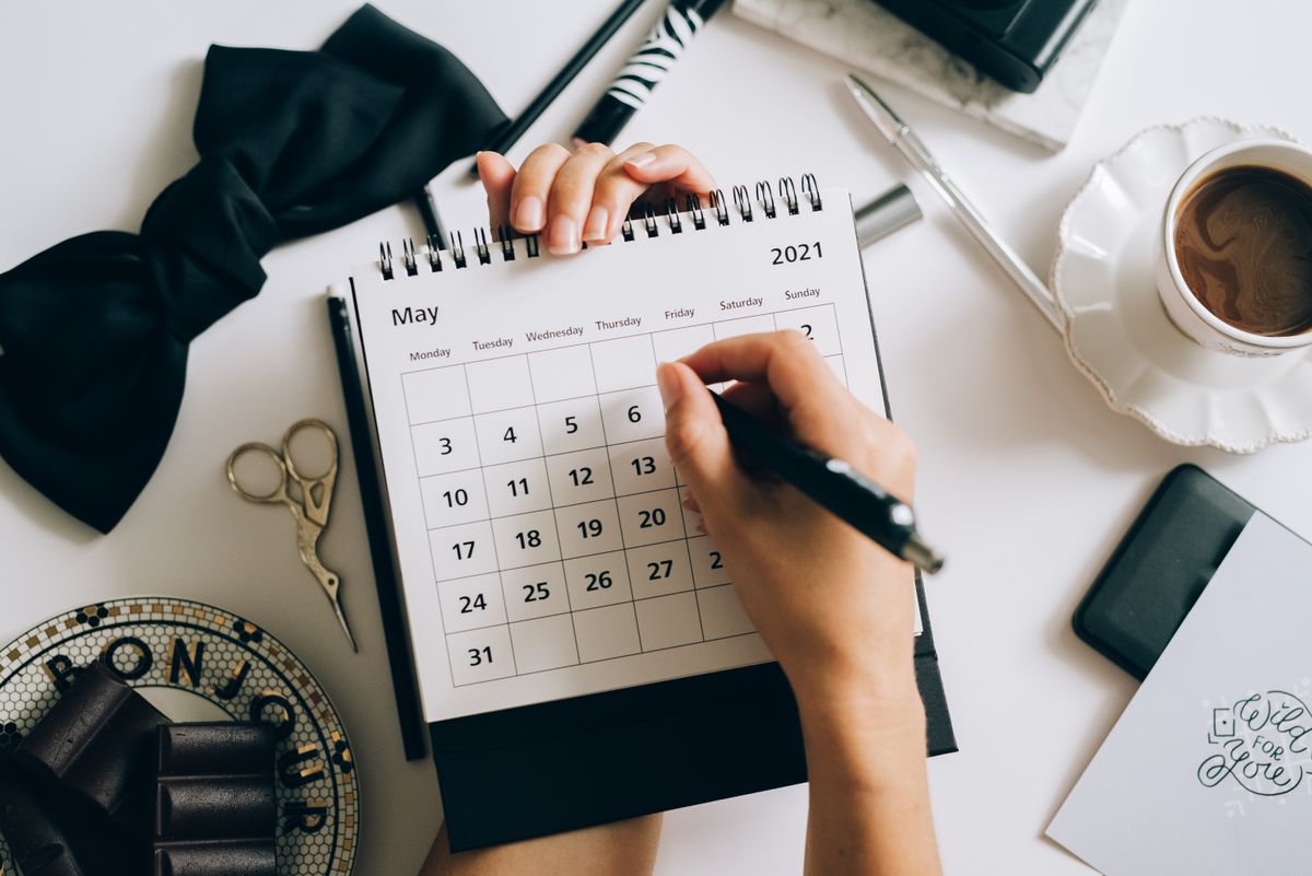 Foto provisória de mãos escrevendo um planejamento em um caderno sobre a mesa